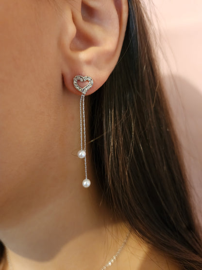 Boucles d'Oreilles Jada en acier inoxydable argenté avec cœur et perles suspendues, portées sur une oreille