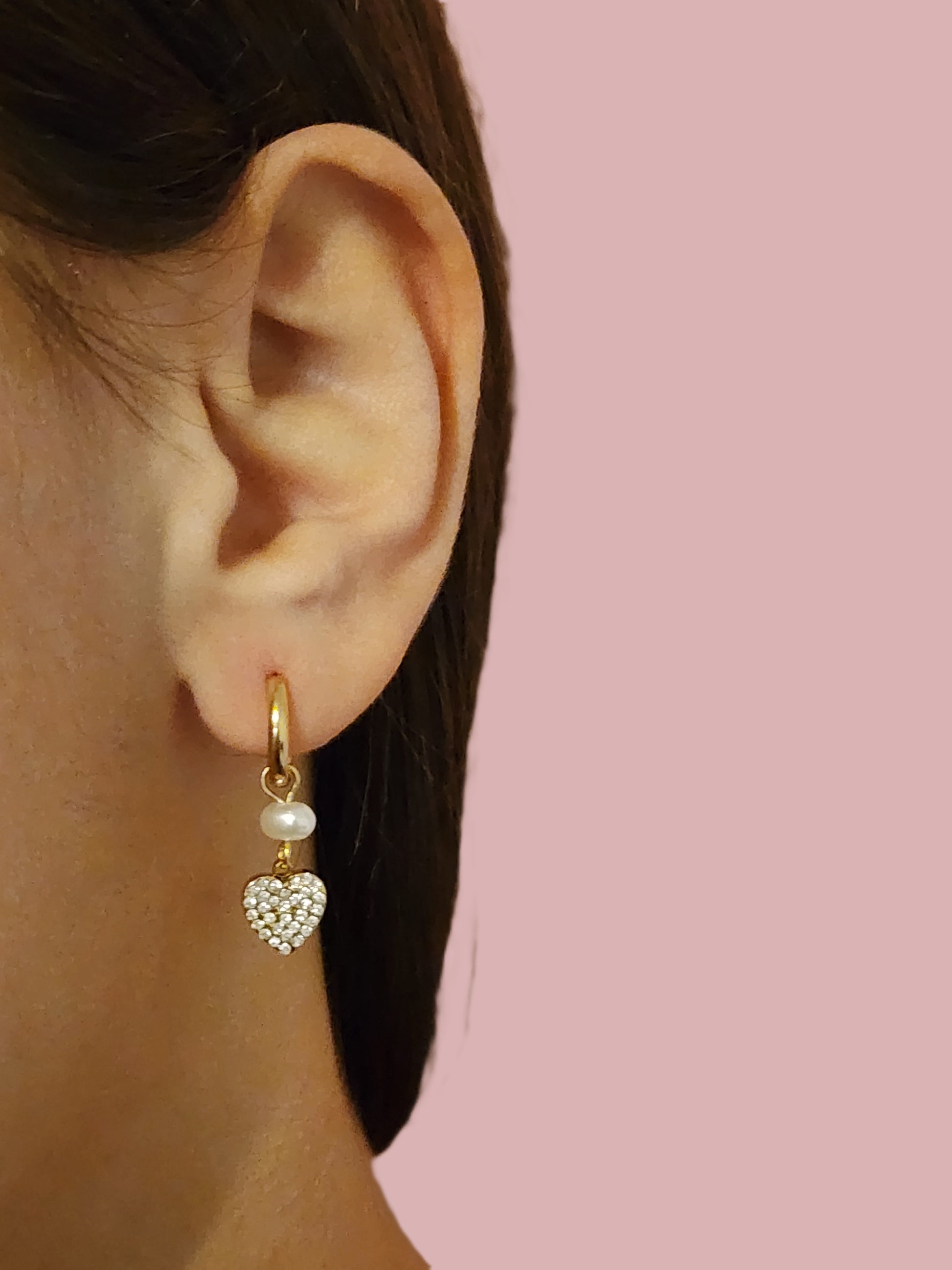 Boucles d'Oreilles Sara en acier inoxydable doré ou argenté avec perle et cœur scintillant, portées sur une oreille